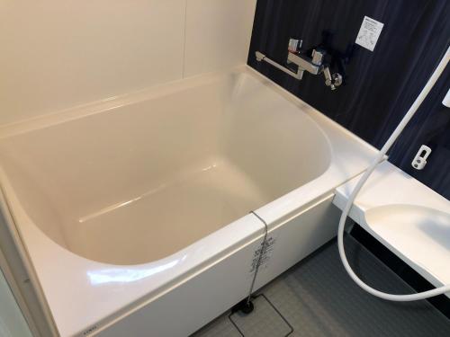 La salle de bains est pourvue d'une baignoire blanche et d'un lavabo. dans l'établissement Methodnet Hanazono B / Vacation STAY 77522, à Chiba