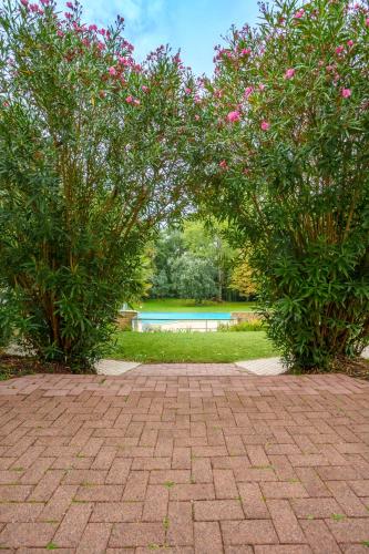 a brick walkway with two trees and a pool at Kyriad Nantes Sud - Bouaye Aéroport in Bouaye