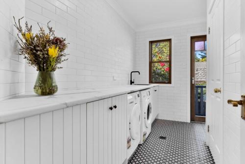 a white kitchen with a vase of flowers on the counter at Twenty 2 Abbey in Leura