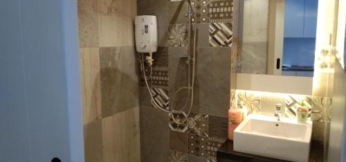 a bathroom with a shower with a sink and a mirror at PINTARMAN SERVICE APRTMENT @ THE STIRLING SUITES in Miri