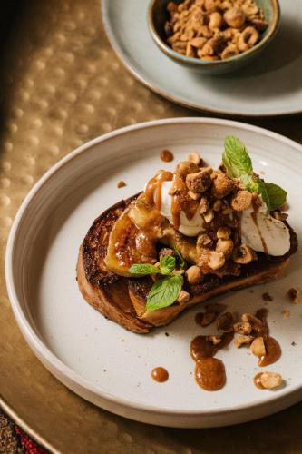 een wit bord met daarop een broodje met nootjes bij Our Habitas AlUla in Al Ula