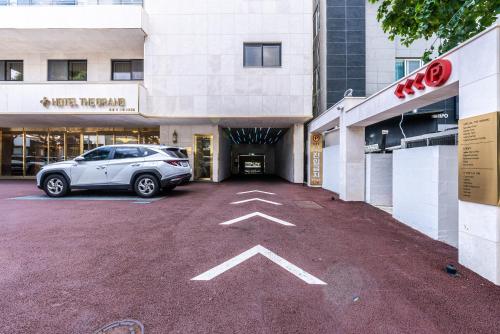 a car parked in a parking lot in front of a building at Hotel The Grang Seogwipo in Seogwipo