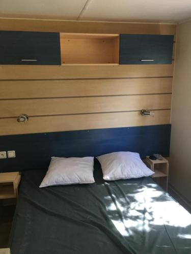 a bedroom with a bed with a blue headboard at Mobile home climatisé en Touraine, calme et ombragé in Trogues