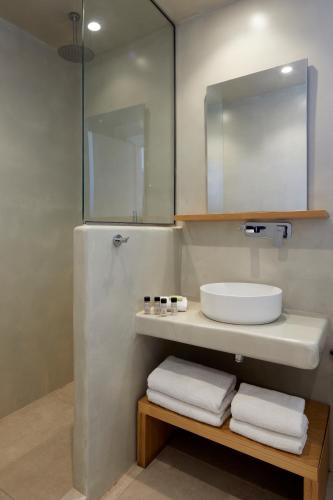 a bathroom with a sink and a mirror and towels at Adorno Oia in Oia