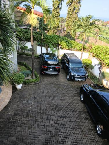 two cars parked in a parking lot with palm trees at Himma's Apartments in Adonkia
