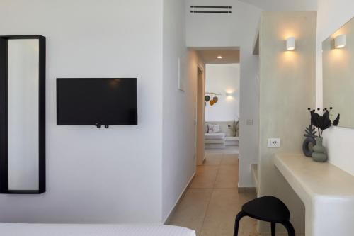 a bedroom with a bed and a tv on a wall at Adorno Oia in Oia