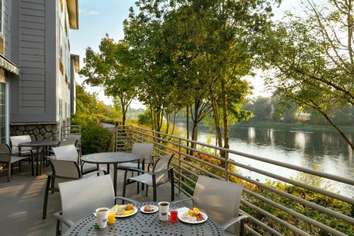 a patio with tables and chairs and a view of a river at Holiday Inn Express Corvallis-On the River by IHG in Corvallis