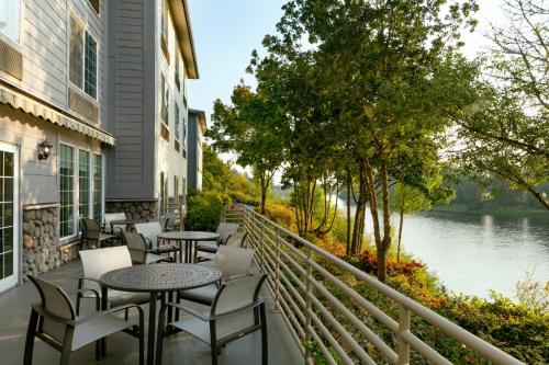 a balcony with tables and chairs overlooking a river at Holiday Inn Express Corvallis-On the River by IHG in Corvallis