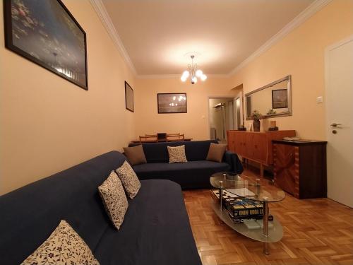 un salon avec un canapé bleu et une table en verre dans l'établissement Cozy three BDRMS central APT at five Filippou str, à Thessalonique