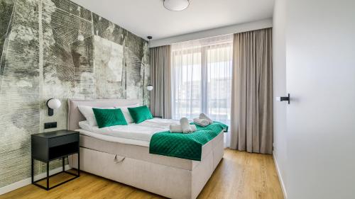 een slaapkamer met een bed met groene kussens bij Plac Unii Centrum - Comfy Apartments in Gdynia
