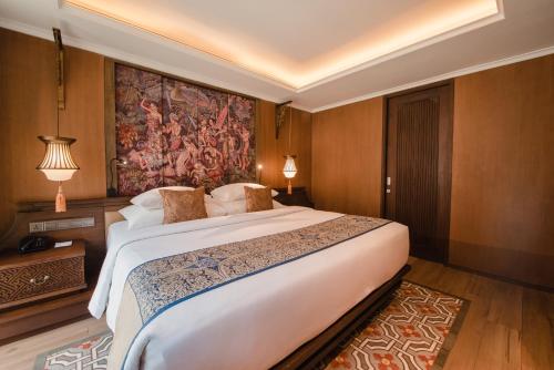 a bedroom with a large bed and a painting on the wall at Ramayana Suites and Resort in Kuta