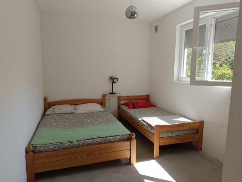 two beds in a small room with a window at Riverhouse Žeger in Prijedor