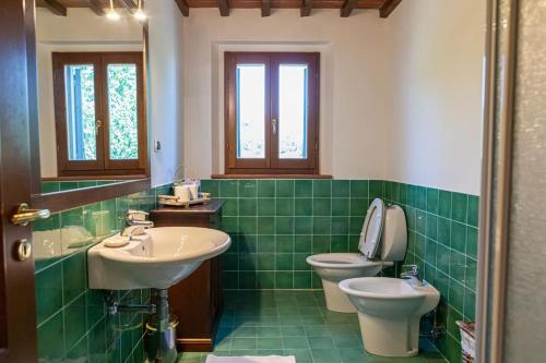 Baño de azulejos verdes con lavabo y aseo en Fienile panoramico nel Chianti, en Greve in Chianti