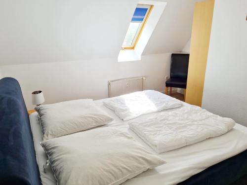 a bed with white sheets and pillows in a room at Schwalbennest 10 in Buchholz