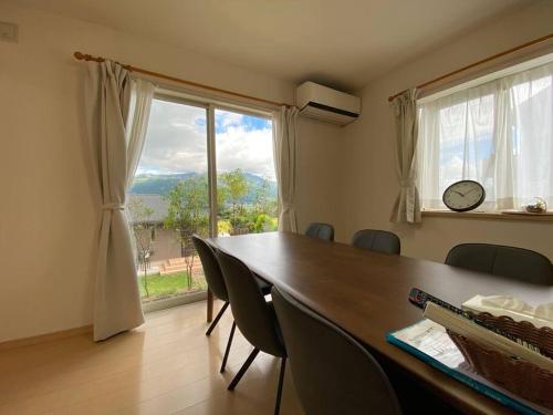 mesa de comedor con sillas y ventana grande en 南あその丘, en Shimoda