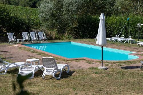 a swimming pool with chairs and an umbrella at Fienile panoramico nel Chianti in Greve in Chianti