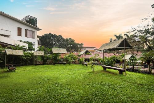 a park with benches and umbrellas and a building at Manas Lifestyle Resort, Igatpuri in Igatpuri