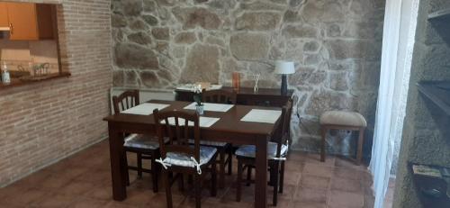 a dining room table with chairs and a stone wall at Apartamento Tui Centro in Tui