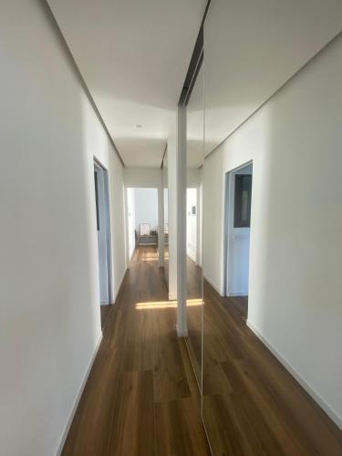 a long hallway with white walls and wood floors and a glass wall at ORO, 8 in Bellano