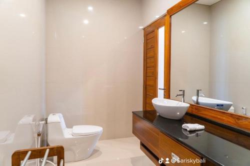 a bathroom with a sink and a toilet and a mirror at Sari Sky Bali in Kubupenlokan