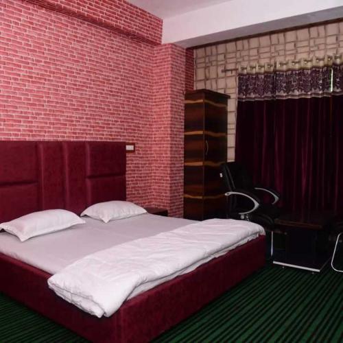a bedroom with a large bed and a red brick wall at Hotel O Graceland in Srīnagar
