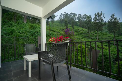 Un balcón con mesa y sillas y una vista en Teaberg Estate Haus, en Munnar