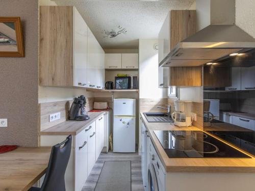 une cuisine avec des appareils électroménagers blancs et des armoires en bois dans l'établissement Studio cosy 4 pers. avec loggia, parking et équipement complet, à deux pas du centre de Cauterets - FR-1-401-78, à Cauterets