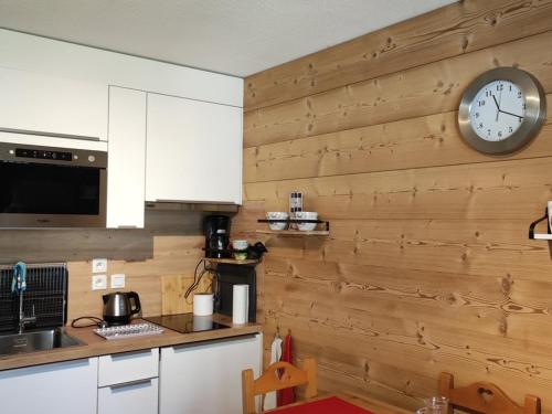 une cuisine avec une horloge sur un mur en bois dans l'établissement À louer 2 pièces au pied des pistes, déco soignée, parking - FR-1-573-101, à Saint-Jean-dʼAulps