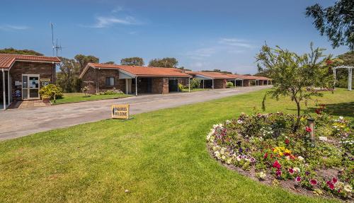 a building with a sign in a yard with flowers at Emu Beach Chalets in Albany