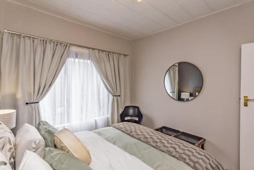 a bedroom with a bed and a mirror and a window at CLASSIC A&W in Sandton