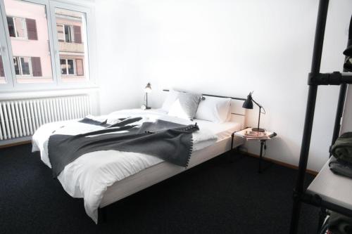 a white bed in a room with a window at Nest - Elsastrasse 16 in Zurich