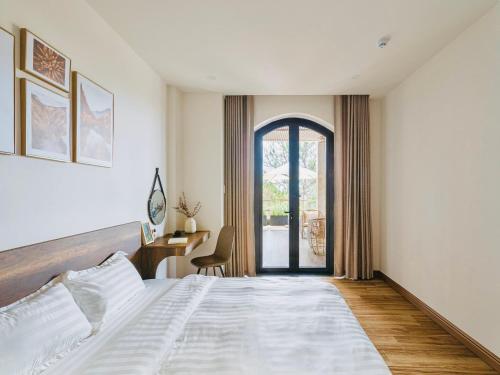 a bedroom with a bed and a desk and a window at Đá Góc Nhà Boutique Hotel in Da Lat
