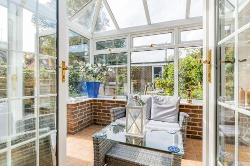 um jardim de Inverno com janelas, uma cadeira e uma mesa de vidro em Chimneys em Poole