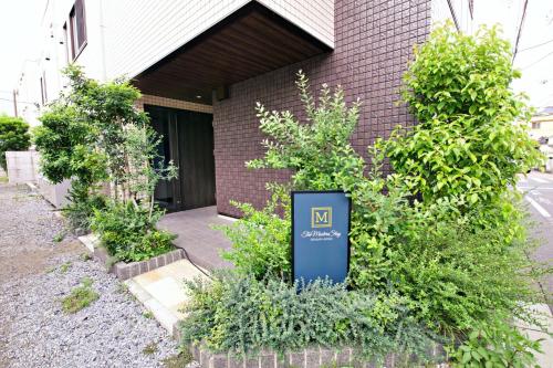 a sign in front of a building with plants at The Masters Stay SETAGAYA KYODO in Tokyo