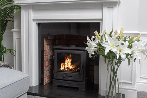 a fireplace with a fire in a living room with flowers at Riversleigh 