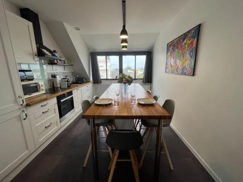 une cuisine avec une table en bois et des chaises. dans l'établissement Le nid, au Pouliguen