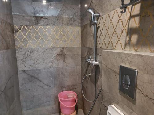 a shower with a pink bucket in a bathroom at Maya Hotel & Restaurant in Agra