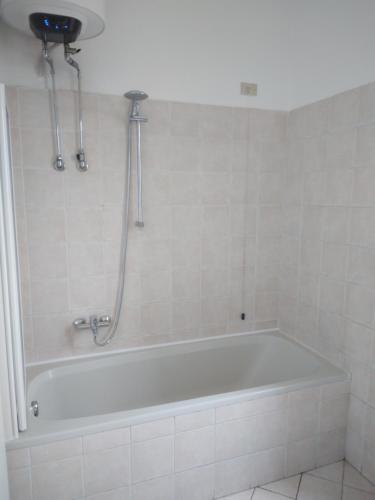 La salle de bains est pourvue d'une baignoire blanche et d'une douche. dans l'établissement Spazioso appartamento Parabiago, à Parabiago