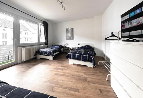 a bedroom with two beds and a large window at #VAZ Apartments RS06 Küche, WLAN, TV, Balkon in Remscheid