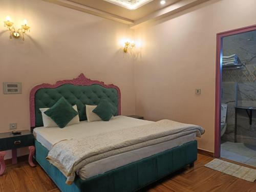 una camera con un grande letto con testiera verde di Maya Hotel & Restaurant ad Agra
