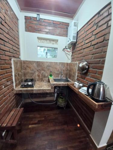 cocina con fregadero y pared de ladrillo en Agora Home, en Wonosobo
