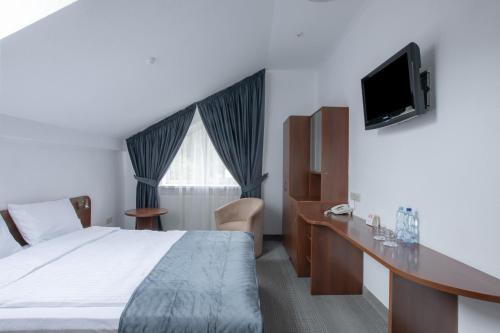 a hotel room with a bed and a desk and a television at Gots - готельно-ресторанний комплекс in Yaremche