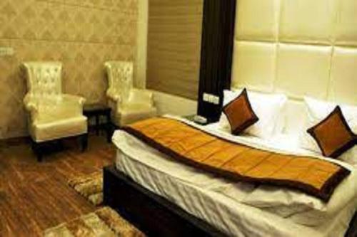 a bedroom with a bed and two chairs in it at Hotel Riya Palace By Standards in Haldwāni