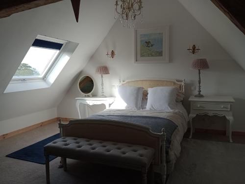 Schlafzimmer mit einem Bett mit einer Bank und einem Fenster in der Unterkunft Le Presbytere in Beauficel