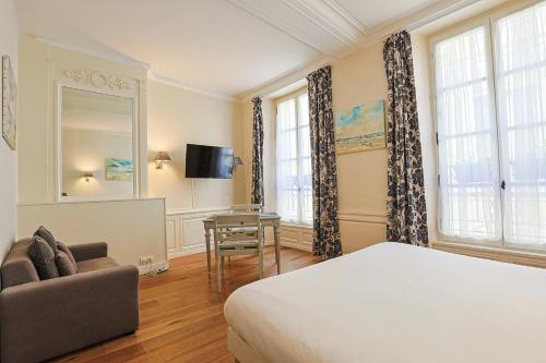 um quarto com uma cama, um sofá e uma mesa em Hôtel François d'O em Caen