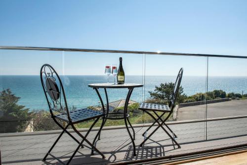 a table with two chairs and a bottle of wine on a balcony at Fulmar in Torpoint