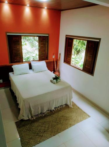 a bedroom with a white bed with two windows at Flat de Irinha Moreré in Cayru