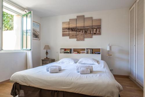 une chambre avec un grand lit blanc avec deux oreillers dans l'établissement Le Petit Moulleau - Appt dans villa classée à 50m de la plage, à La Teste-de-Buch
