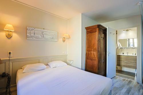a bedroom with a white bed and a wooden cabinet at Hôtel François d'O in Caen