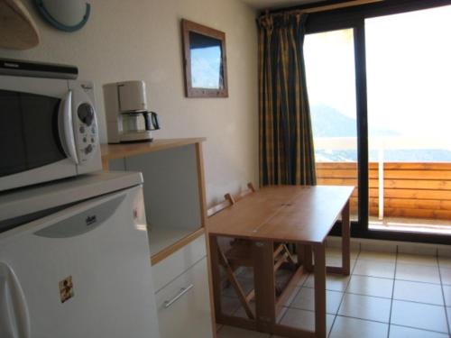 une cuisine avec une petite table et un micro-ondes dans l'établissement Appartement ensoleillé pour 5 pers, balcon sud, proche remontées et commerces, animaux acceptés - FR-1-405-94, à L'Alpe-d'Huez